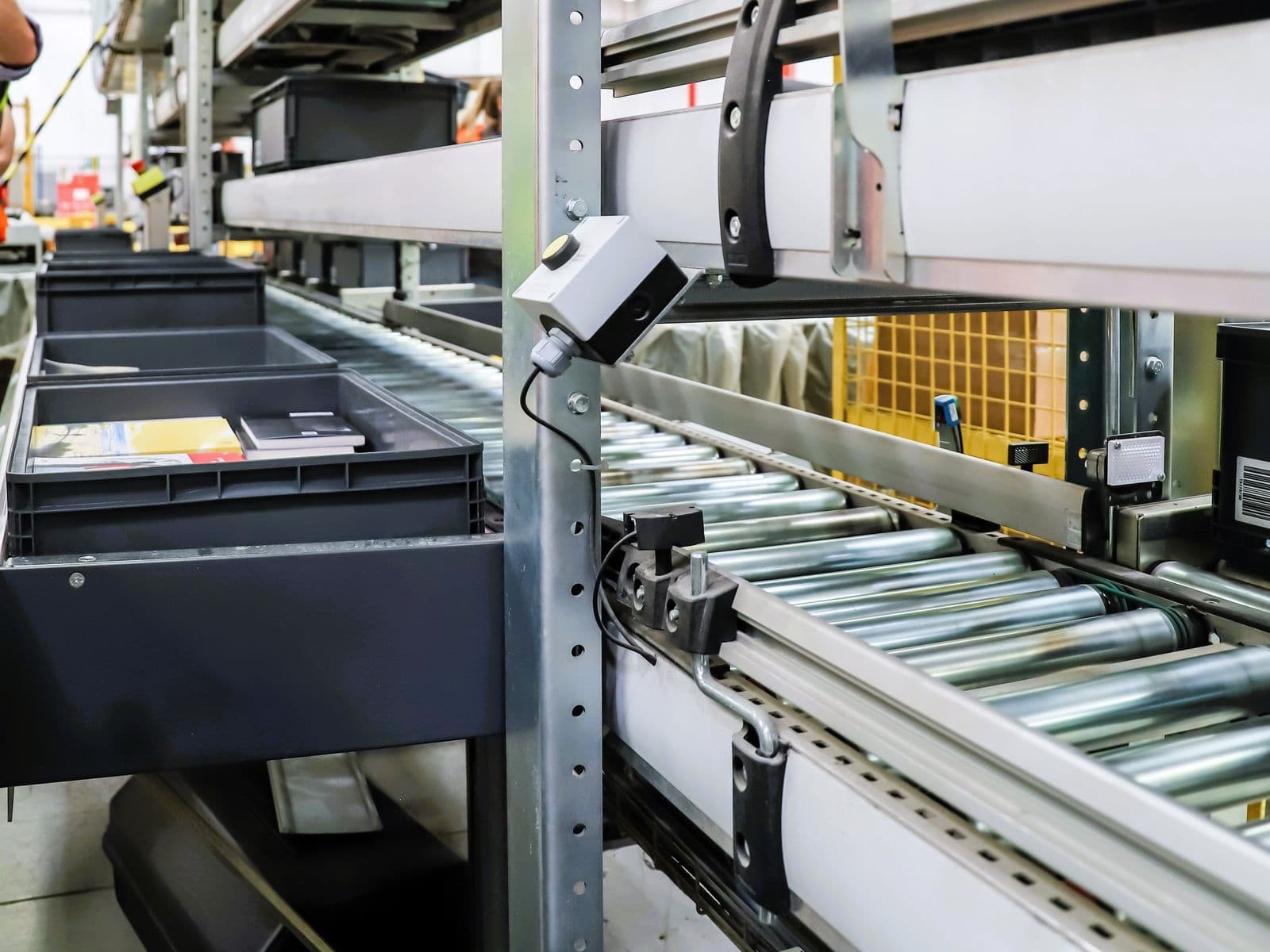 Camera mounted above a roller conveyor carrying totes in a warehouse