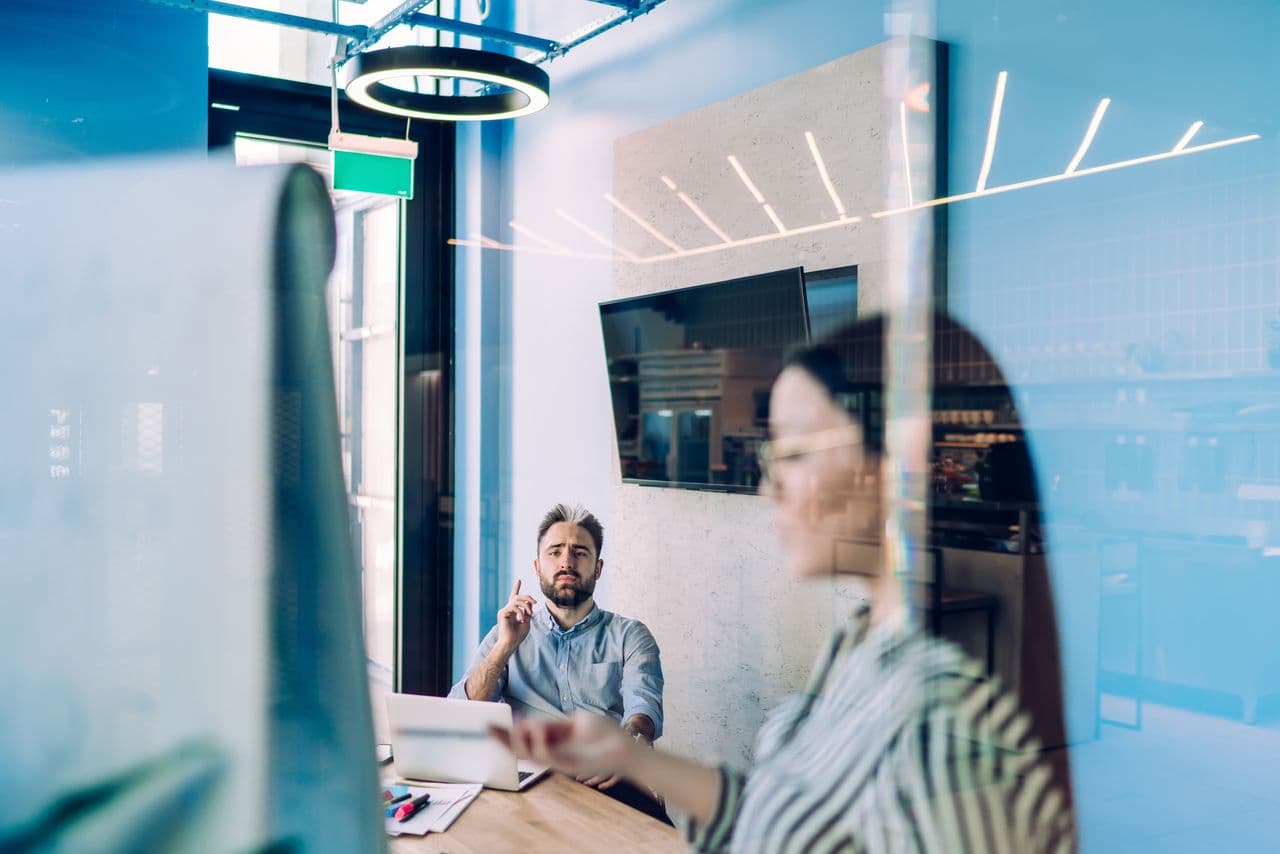 Colleagues talking in a glass-walled meeting room