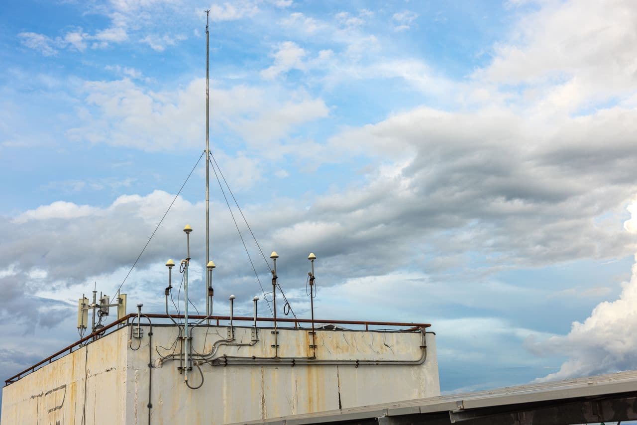 Antenna mast on a rooftop against a cloudy sky