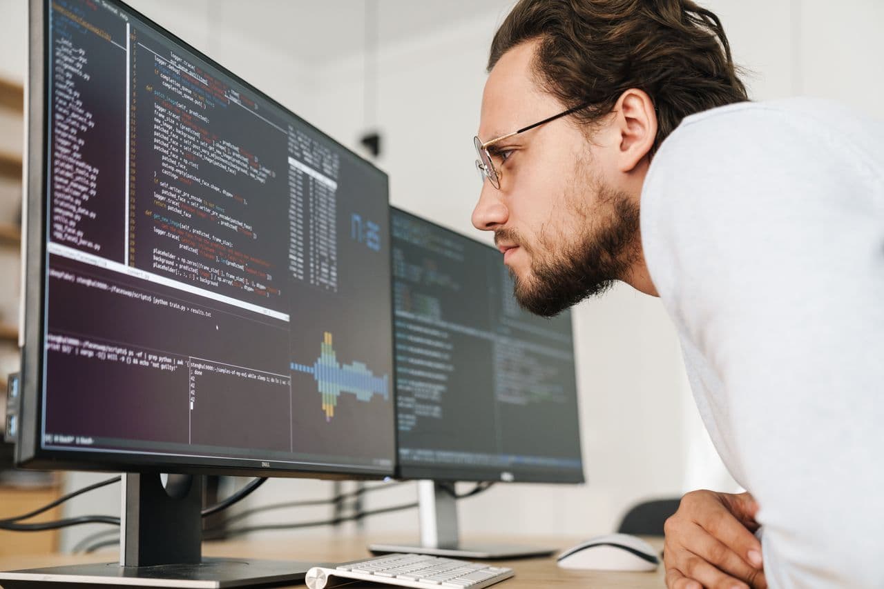 Engineer reading code on a multi-monitor workstation