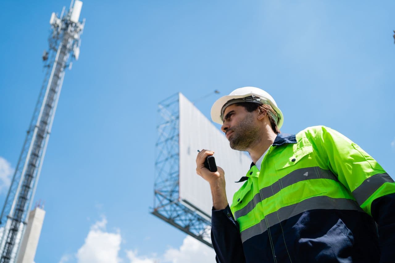 Site supervisor on a radio beside a mast