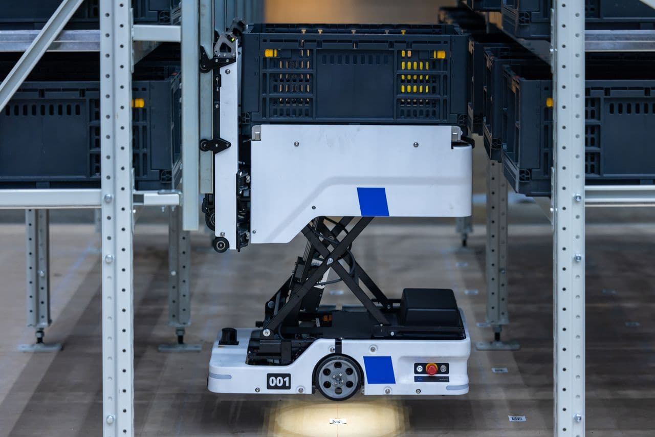 Case-handling robot lifting a crate from warehouse shelving